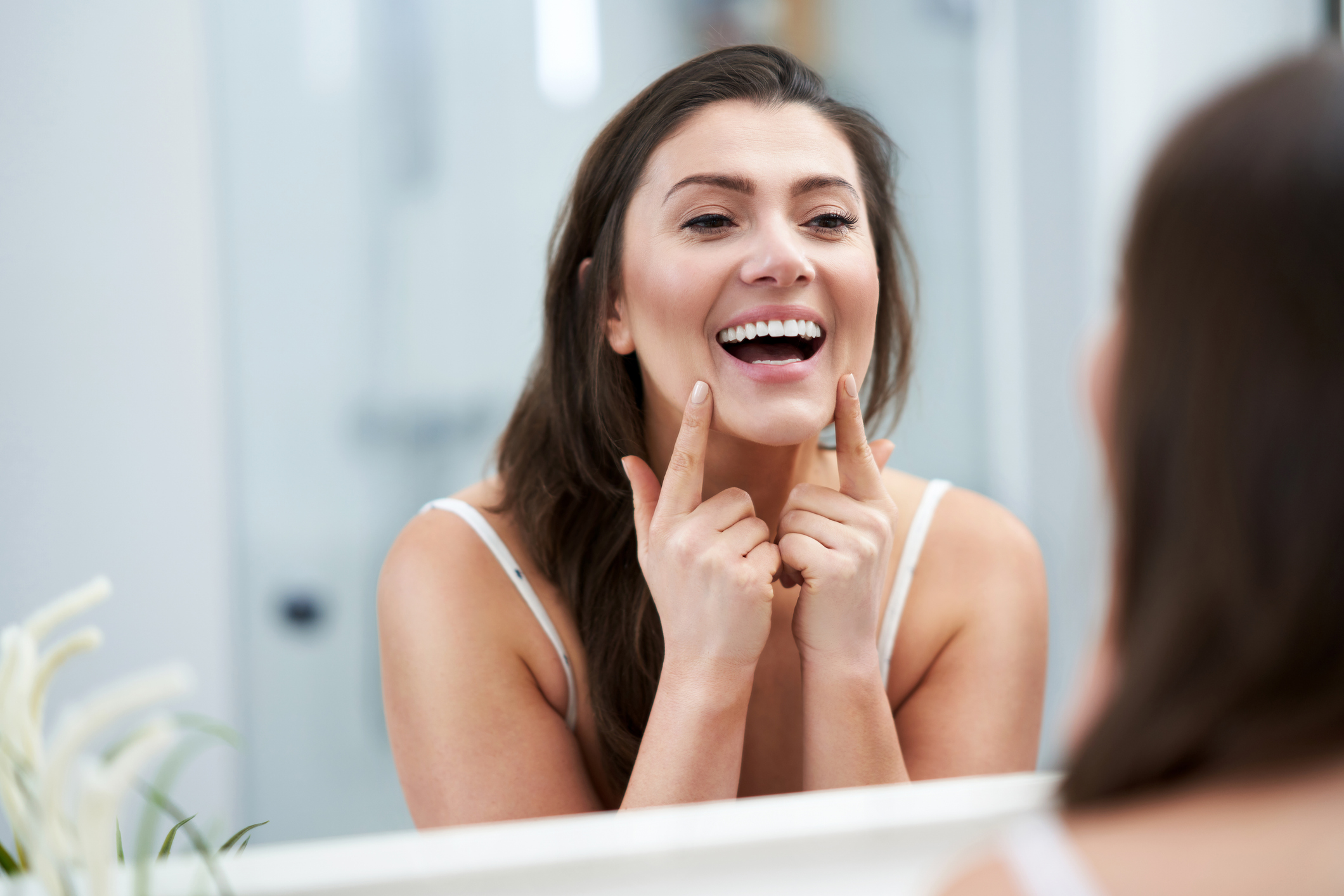 Woman looking at her smile with veneers in the mirror.